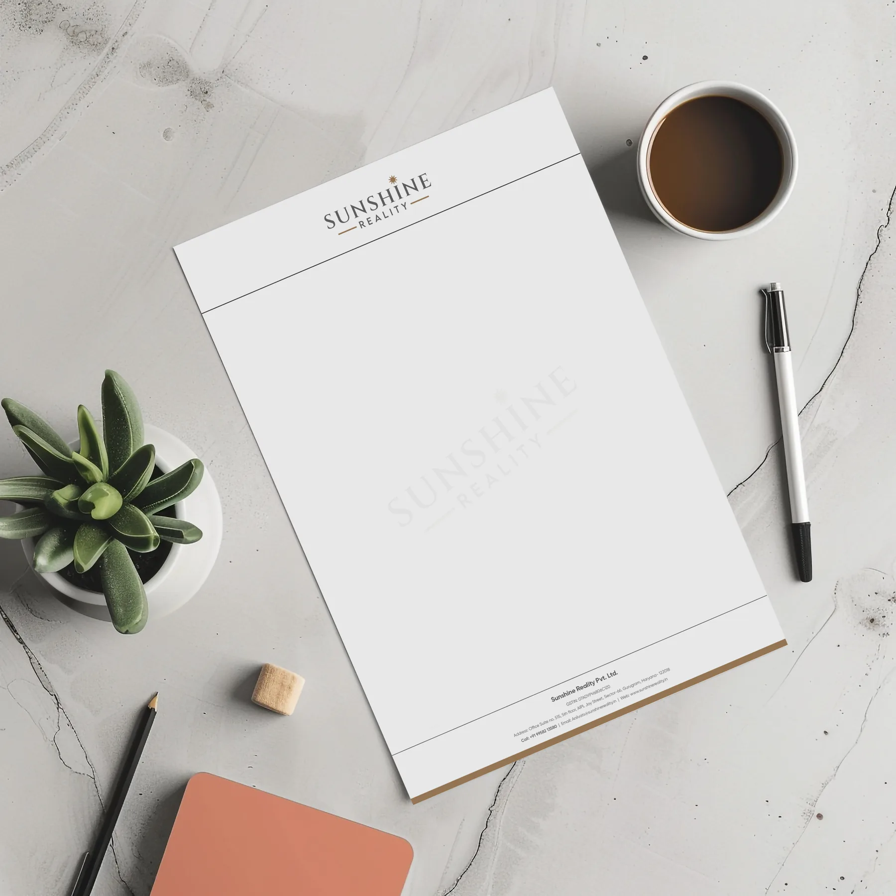 Click to view full size Sunshine Reality letterhead on a marble desk with pen, plant and notebook